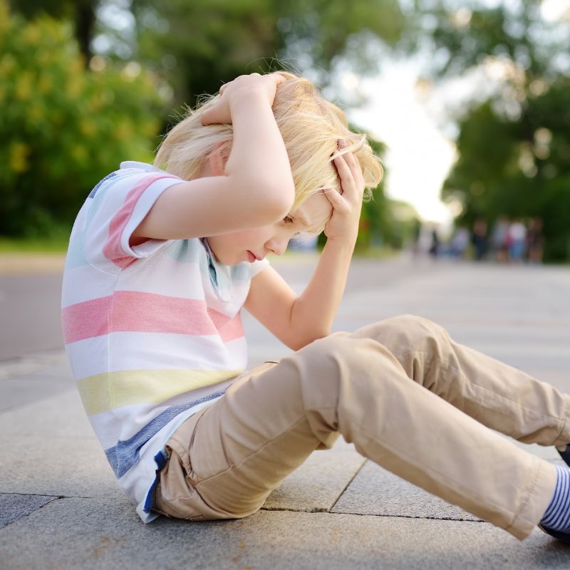 young child holding his head after a concussion